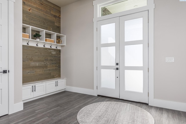 mudroom with dark wood-type flooring, baseboards, wooden walls, and french doors