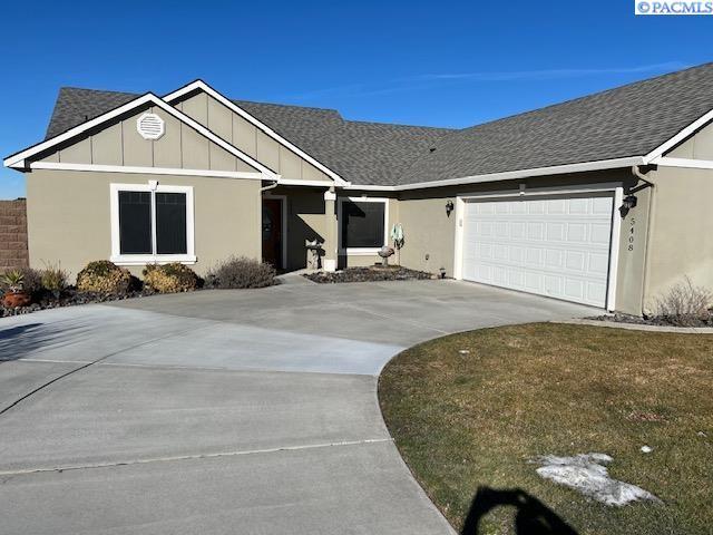 single story home featuring driveway, a shingled roof, and an attached garage