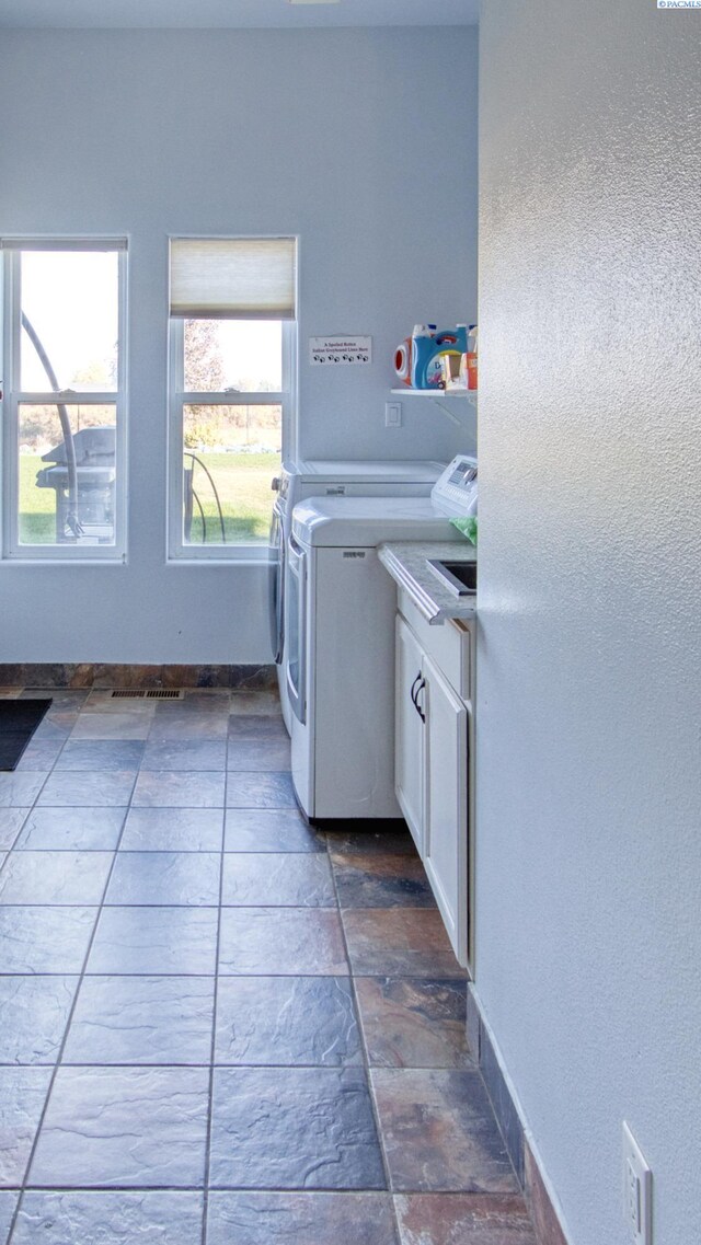 laundry area featuring separate washer and dryer and cabinets