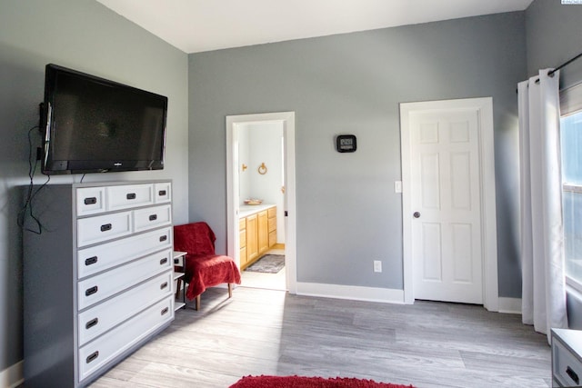 bedroom with light hardwood / wood-style floors and ensuite bathroom