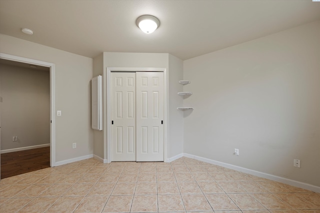 unfurnished bedroom with light tile patterned flooring and a closet