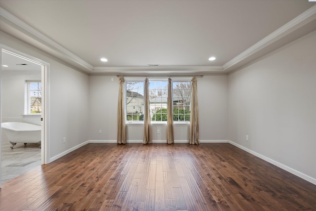 empty room with crown molding, dark hardwood / wood-style floors, and a tray ceiling