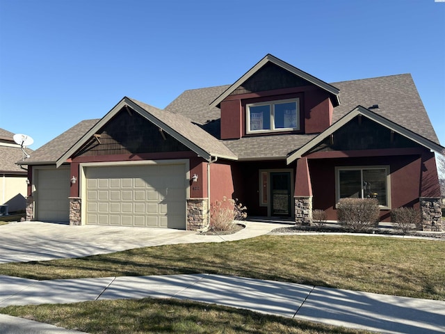 craftsman inspired home with stone siding, a front lawn, an attached garage, and driveway