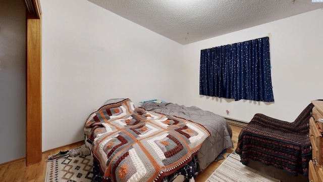 1735 NE Wheatland Dr, Pullman, WA 99163 - bedroom featuring baseboards, a textured ceiling, and wood finished floors