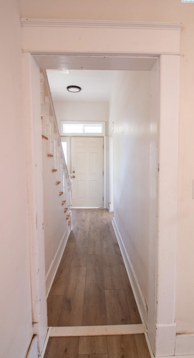 corridor with stairway, hardwood / wood-style flooring, and baseboards