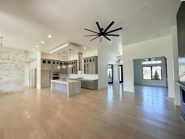 3408 Royce Ln, Pasco, WA 99301 - kitchen featuring a ceiling fan, open floor plan, a kitchen island with sink, light countertops, and a towering ceiling
