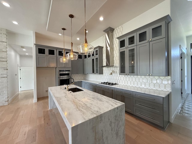 3408 Royce Ln, Pasco, WA 99301 - kitchen featuring gray cabinetry, wall chimney range hood, stainless steel double oven, light wood finished floors, and recessed lighting