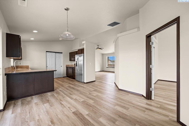 kitchen with dark brown cabinetry, visible vents, light wood-type flooring, a sink, and stainless steel fridge with ice dispenser
