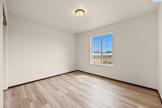 empty room featuring baseboards and light wood finished floors