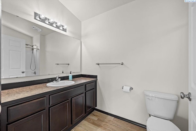 bathroom with walk in shower, vanity, toilet, wood finished floors, and lofted ceiling