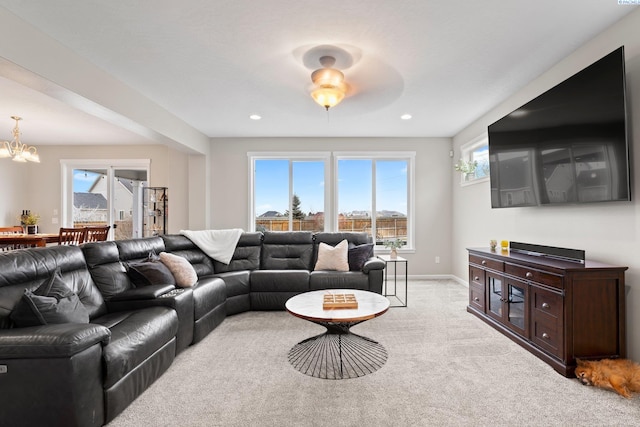 living area featuring light carpet, a chandelier, a wealth of natural light, and baseboards