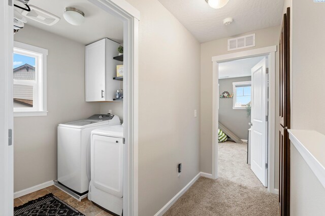 clothes washing area with visible vents, cabinet space, baseboards, and separate washer and dryer