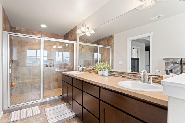 full bath featuring double vanity, a sink, visible vents, and a shower stall