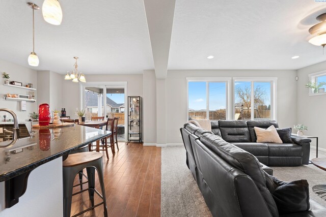 living room with a notable chandelier, baseboards, wood finished floors, and recessed lighting