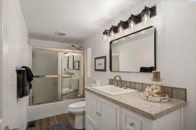 518 Wright Ave, Richland, WA 99352 - full bathroom with toilet, vanity, wood finished floors, bath / shower combo with glass door, and a textured wall