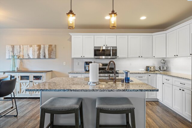 kitchen featuring decorative light fixtures, stainless steel appliances, dark hardwood / wood-style floors, and white cabinets