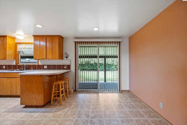508 W Concord Ave, Grandview, WA 98930 - kitchen featuring tasteful backsplash, light countertops, a breakfast bar area, brown cabinets, and a peninsula