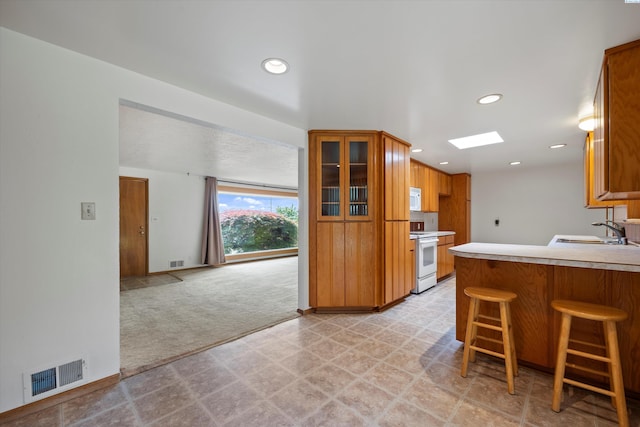 508 W Concord Ave, Grandview, WA 98930 - kitchen featuring white appliances, glass insert cabinets, a skylight, light flooring, and a peninsula