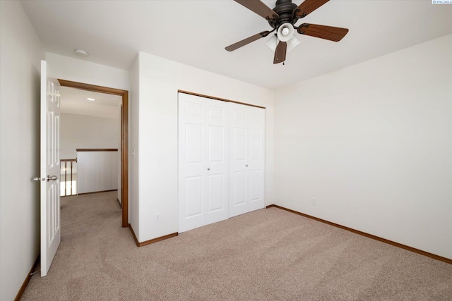 unfurnished bedroom featuring ceiling fan, baseboards, a closet, and light colored carpet