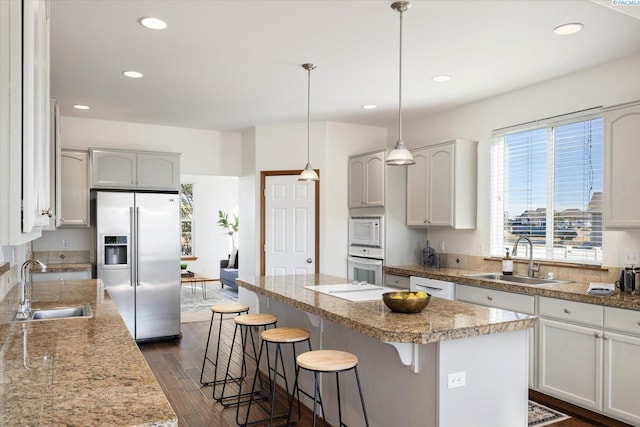 kitchen with white appliances, a kitchen bar, a sink, and a center island