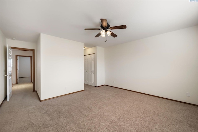 unfurnished bedroom featuring light carpet, a ceiling fan, baseboards, and a closet