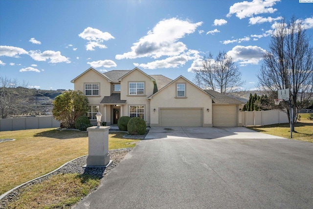 traditional-style house featuring stucco siding, fence, a garage, driveway, and a front lawn