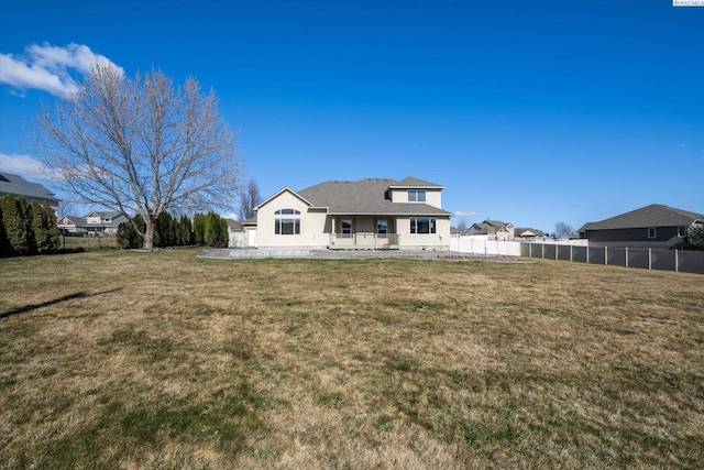 back of property with a lawn, a patio area, and fence