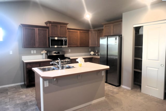 kitchen featuring a breakfast bar, lofted ceiling, sink, a kitchen island with sink, and stainless steel appliances