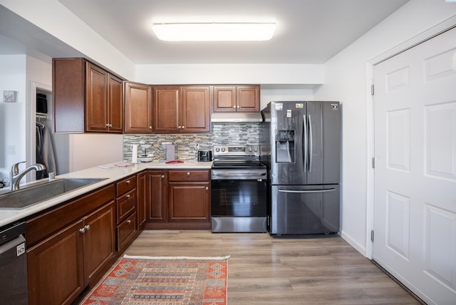 kitchen featuring appliances with stainless steel finishes, sink, backsplash, and light hardwood / wood-style floors