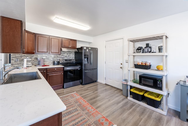 kitchen featuring appliances with stainless steel finishes, sink, light hardwood / wood-style flooring, and decorative backsplash