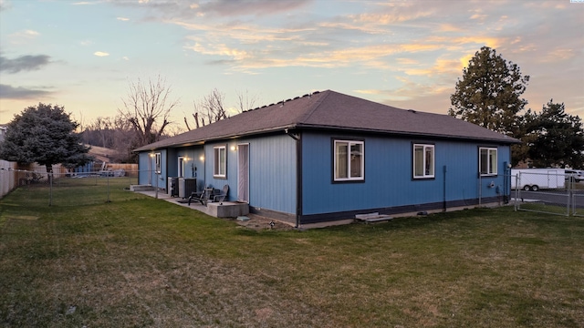 property exterior at dusk featuring a patio, a lawn, and central air condition unit