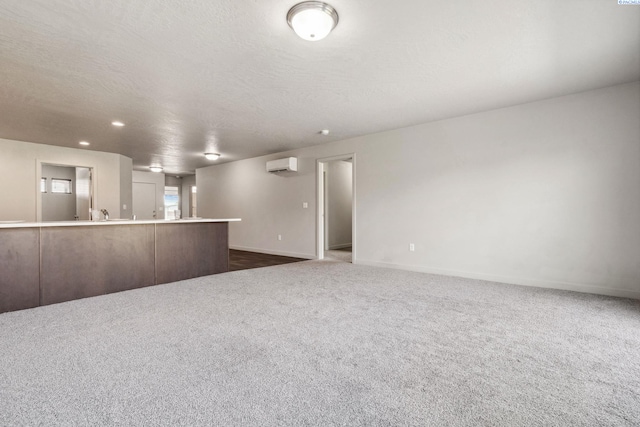 407 Dawson Ln, Pasco, WA 99301 - unfurnished living room featuring a wall mounted air conditioner, baseboards, dark carpet, and a textured ceiling