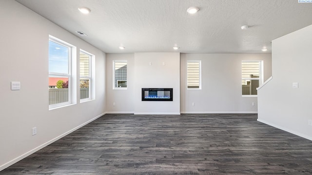 656 S Zeelar St, Kennewick, WA 99336 - unfurnished living room featuring dark wood-style flooring, plenty of natural light, a textured ceiling, baseboards, and a glass covered fireplace