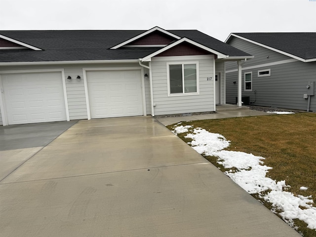 view of front facade featuring a garage, concrete driveway, roof with shingles, and a front lawn