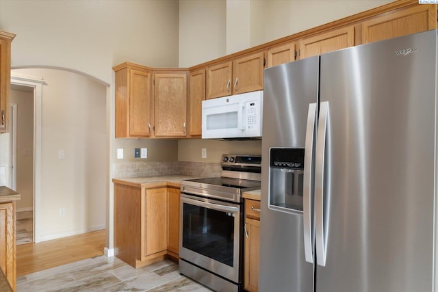 2704 Iris St, West Richland, WA 99353 - kitchen with appliances with stainless steel finishes, light countertops, arched walkways, and light wood finished floors
