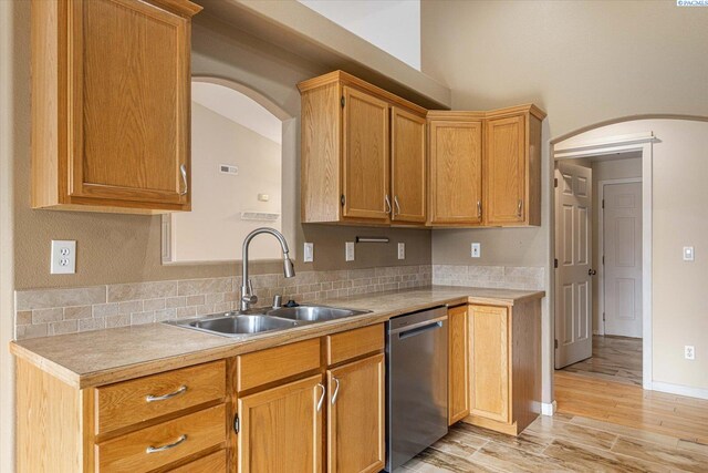 2704 Iris St, West Richland, WA 99353 - kitchen with dishwasher, a sink, arched walkways, light countertops, and light wood-type flooring