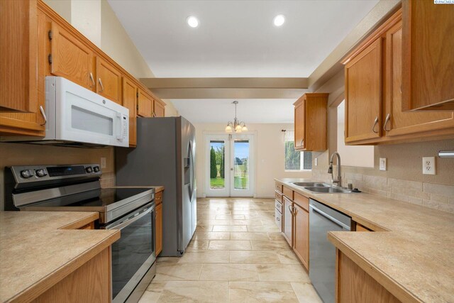 2704 Iris St, West Richland, WA 99353 - kitchen featuring stainless steel appliances, a sink, light countertops, a chandelier, and brown cabinetry