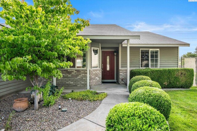 2704 Iris St, West Richland, WA 99353 - doorway to property with brick siding, a shingled roof, and a porch