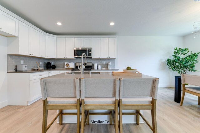 2945 S Penn St, Kennewick, WA 99338 - kitchen featuring stainless steel microwave, decorative backsplash, light wood-style flooring, a sink, and recessed lighting