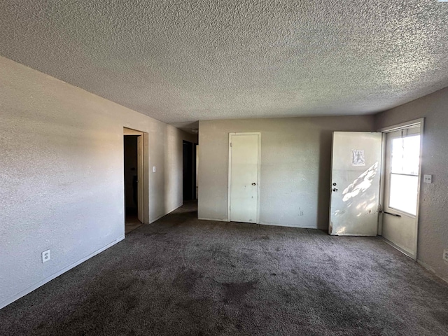 unfurnished bedroom with a textured ceiling and dark carpet