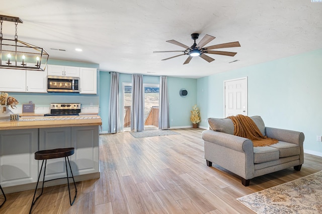 living room with ceiling fan and light hardwood / wood-style floors