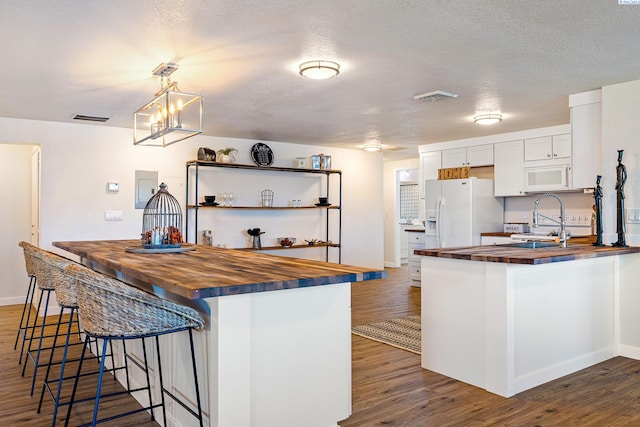 kitchen with dark wood-type flooring, butcher block countertops, pendant lighting, white appliances, and white cabinets