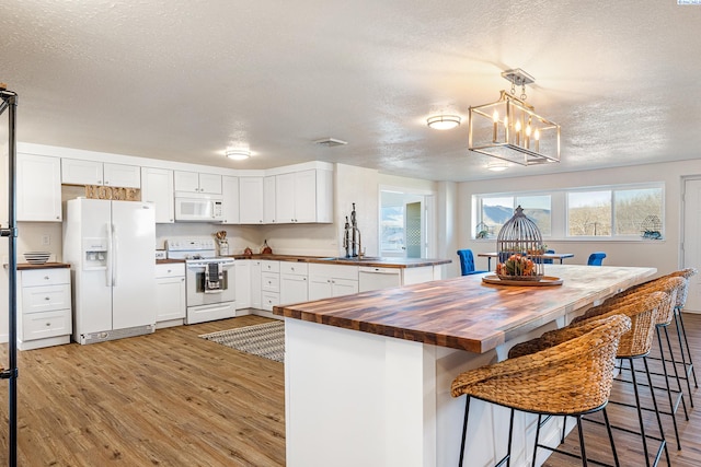 kitchen with wood counters, white appliances, pendant lighting, and white cabinets