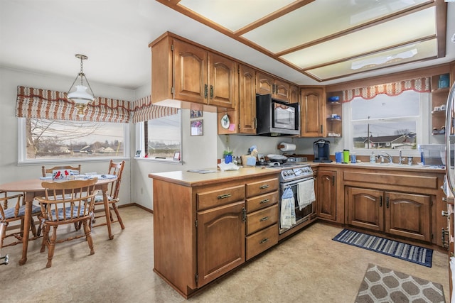 kitchen featuring sink, kitchen peninsula, stainless steel stove, and decorative light fixtures