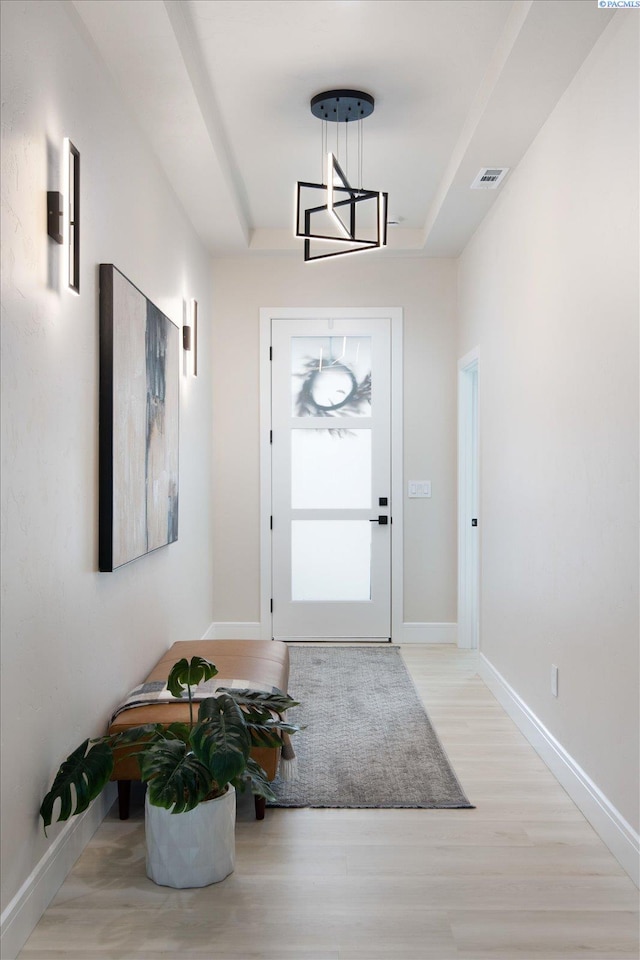 doorway featuring a raised ceiling and light hardwood / wood-style floors