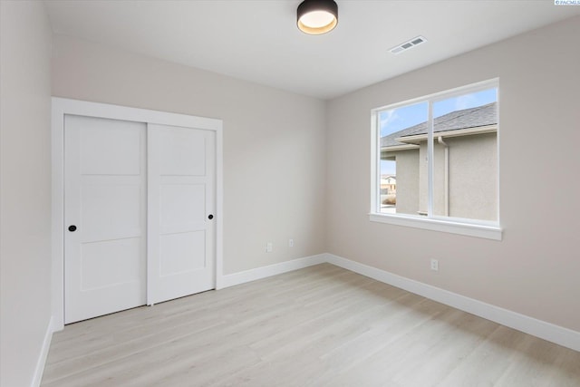 unfurnished bedroom featuring light hardwood / wood-style floors and a closet