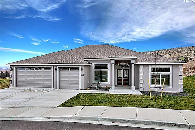 ranch-style house featuring a garage, a front yard, driveway, and stucco siding