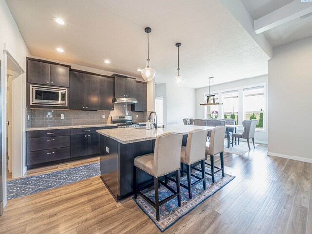 5593 S Lyle Pl, Kennewick, WA 99337 - kitchen featuring stainless steel appliances, under cabinet range hood, light wood-type flooring, a breakfast bar area, and recessed lighting