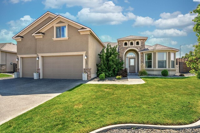 mediterranean / spanish-style house featuring a front yard, stucco siding, driveway, and stone siding