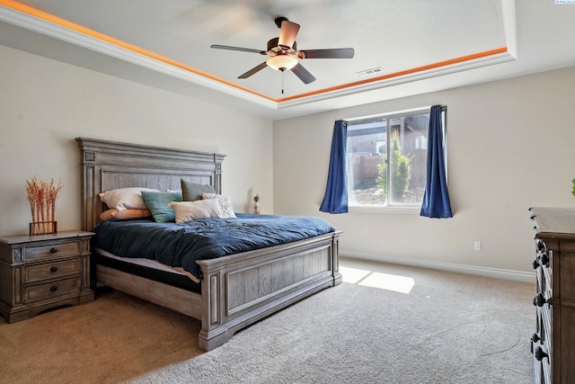 bedroom featuring a tray ceiling, a ceiling fan, visible vents, baseboards, and carpet floors